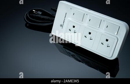 Power strip with three electrical standard socket on black background. White universal plug with overload protection. Fire resistant material for Stock Photo