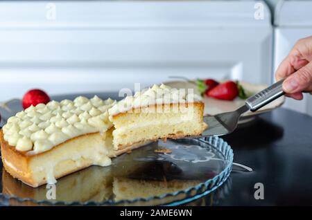 The woman is putting creamy cake and  strawberry on a plate. Stock Photo