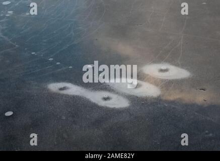 Water on ice melts it and forms various patterns on the ice surface Stock Photo