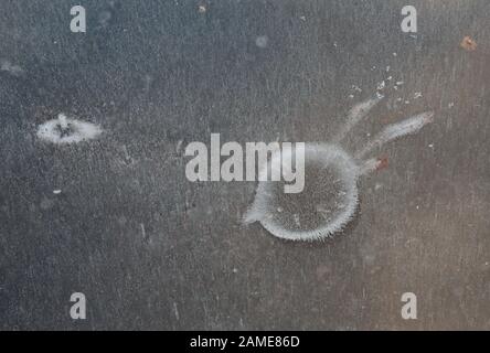 Water on ice melts it and forms various patterns on the ice surface Stock Photo