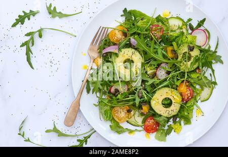 Vegan. Plate of avocado, tomato and rocket salad Stock Photo