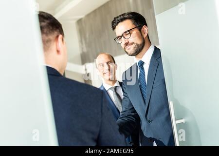 Group of confident business people greeting with a handshake at business meeting in modern office or closing the deal agreement by shaking hands. Stock Photo