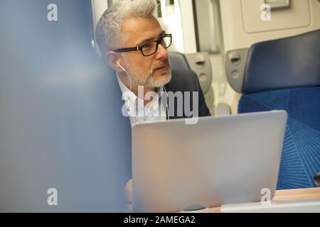 Businessman commuting by train, talking on phone Stock Photo