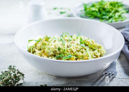Green risotto with broccoli, green peas and sprouts in a white plate. Healthy vegan food concept. Stock Photo