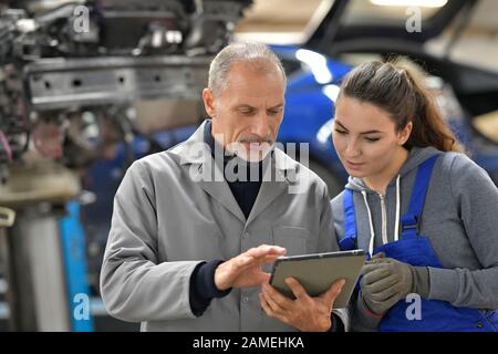 Apprentice with instructor using tablet in workshop Stock Photo