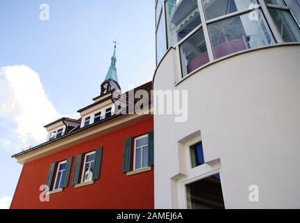 older building with red facade and blue sky and modern extension, Stock Photo