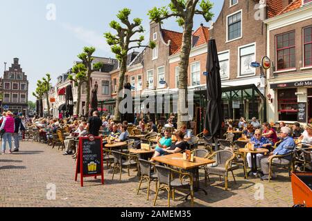 Haarlem, Netherlands - May 28 2019: People enjoy drinks at the tables of bar and restaurants in Haarlem old town with its famous Dutch architecture on Stock Photo