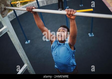 Fit young black man doing pull ups at an outdoor gym  Stock Photo