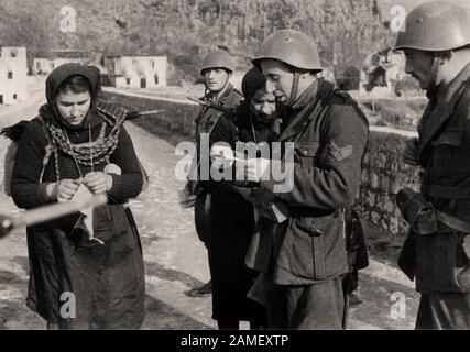 Italian at World War II. Italian soldiers guarding a bridge check the I.D.s of two Montenegrin women, winter of 1942 Stock Photo