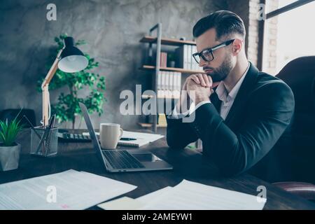 Profile photo of focused business brunet guy looking notebook table reading colleagues email letters analyzing reports wear specs blazer shirt suit Stock Photo