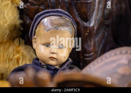 Antique vIntage doll of a little boy with scratched ceramic face, blue cap and blue clothing Stock Photo