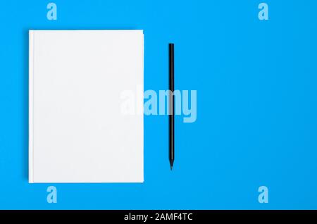 Mockup of closed blank square book and black pencil at colored textured paper background Stock Photo