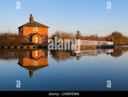 A canal boat passes a house on the Llangollen branch of the Shropshire Union Canal at Whixall, Shropshire. Stock Photo