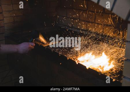 Cooking on fire in a restaurant. Cook inflates the coals. flying sparks. Stock Photo