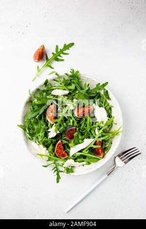 Delicious salad with figs, arugula and goat cheese on white plate, top view, copy space Stock Photo