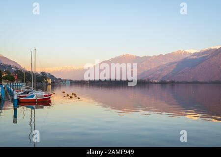 Colorful red boats on stunning mountain lake in Alps during sunset,panorama of Iseo lake from the city of Lovere,Bergamo,Lombardy Italy. Stock Photo