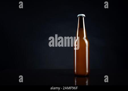 Cold unopened bottle of beer with cap on black background. Glass of refrigerated wheat or lager beer on dark background Stock Photo