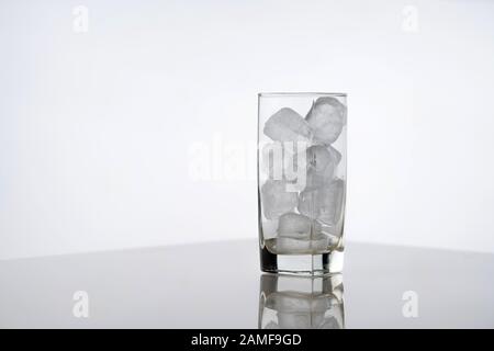Glass full of ice on white background. Icy glass with ice cubes with no drink, preparation before mixing a cocktail Stock Photo