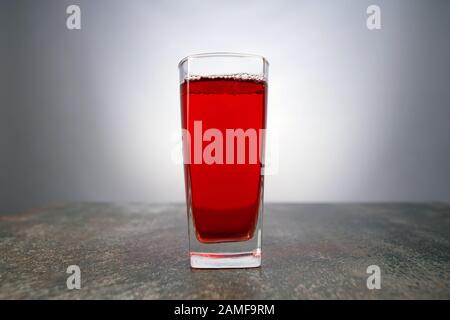 Glass of grape juice on light background. Fresh cocktail glass of red coloured beverage on the table Stock Photo