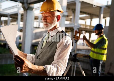Two satisfied engineers talking at building site with construction structure in background Stock Photo