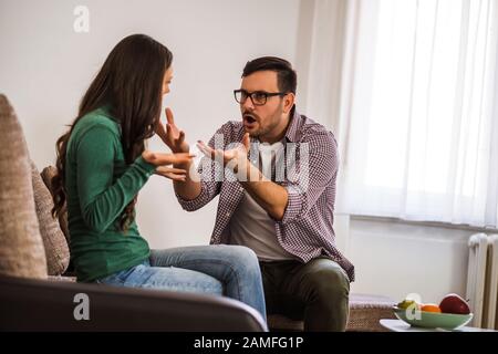 Man and woman are sitting at sofa and arguing. Relationship problems. Stock Photo