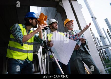 Two satisfied engineers talking at building site with construction structure in background Stock Photo