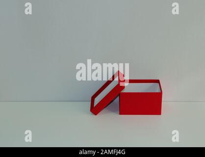 Closeup empty red paper box on white wooden table with lid leans against the box, selective focus, plastic free concept Stock Photo
