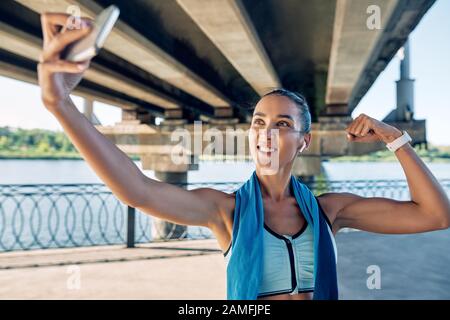 Beautiful sporty woman making selfie flexing her muscles. Sport concept Stock Photo