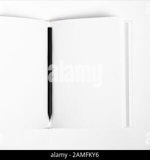 Mockup of closed blank square book and black pencil at white textured paper background Stock Photo