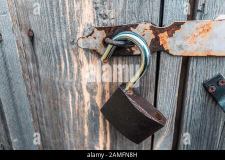 An open padlock hanging on the rotten wooden doors of an old barn Stock Photo