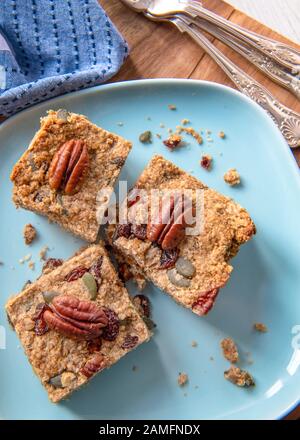 Plant based  vegan cake ,recipe filled with nuts fruit and oats  pieces placed on a blue plate  copy space in background Stock Photo