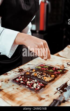 cropped view of chocolatier near dark chocolate bars Stock Photo