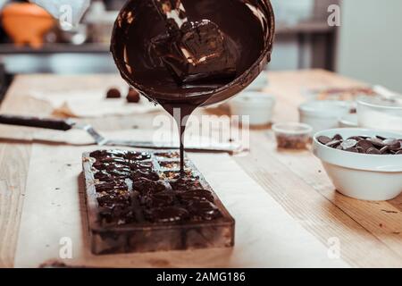 Closeup of squeezing filling of salted caramel cream from confectionery bag  into candy molds for preparing handmade chocolate pralines Stock Photo -  Alamy