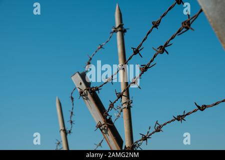 barbwire closeup on fence, barbed wire on blue sky - Stock Photo