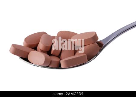 Vitamin pills on tablespoon isolated on white. Macro photography, food supplements. Concept for diet, health and nutrition. Stock Photo