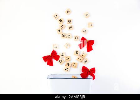 Text, message, letter scattered in white rectangular bucket with red bows isolated on white background. Stock Photo
