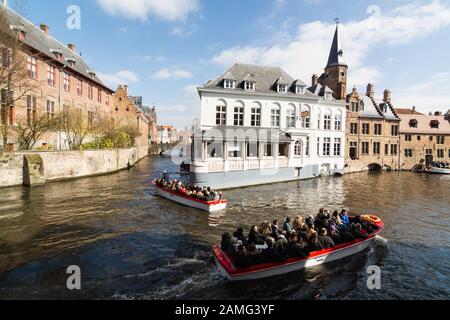 Bruges, Belgium - March 2018: tourists having a boat tour on the city Rozenhoedkaai canals Stock Photo