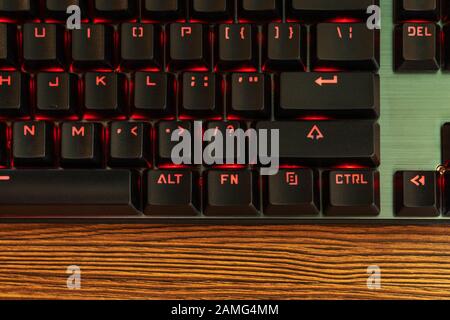 part of the black keyboard with a red backlight near the enter key Stock Photo