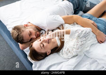 high angle view of handsome man hugging attractive and smiling woman in apartment Stock Photo