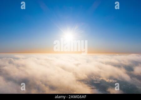 Aerial view above clouds during the sunny winter day Blue sky, white clouds with magic and soft sun light Stock Photo