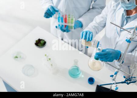 cropped view of biologists in white coats doing test in lab Stock Photo
