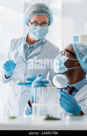 african american biologists talking with colleague and pointing with finger at test tubes Stock Photo