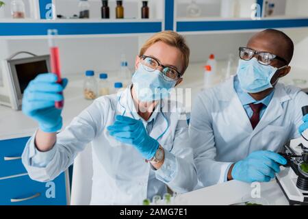 selective focus of multicultural biologists looking at test tube in lab Stock Photo