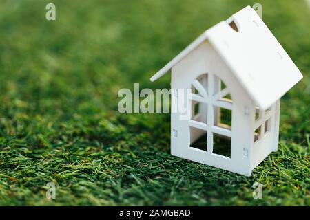 Miniature wooden white house on green grass. Property investment and house mortgage financial real estate concept. Stock Photo