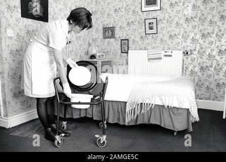 Carer cleaning resident's comode, residential home for the elderly, Nottingham UK 1995 Stock Photo