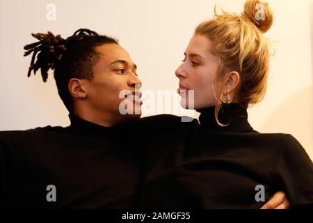 Young intercultural caucasian-hispanic student couple posing on sofa. Stock Photo
