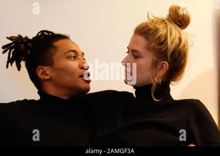 Young intercultural caucasian-hispanic student couple posing on sofa. Stock Photo