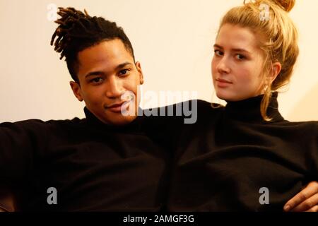 Young intercultural caucasian-hispanic student couple posing on sofa. Stock Photo