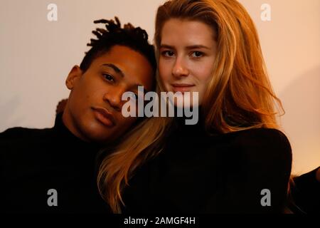 Young intercultural caucasian-hispanic student couple posing on sofa. Stock Photo