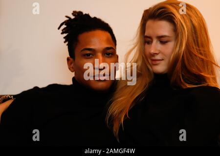 Young intercultural caucasian-hispanic student couple posing on sofa. Stock Photo